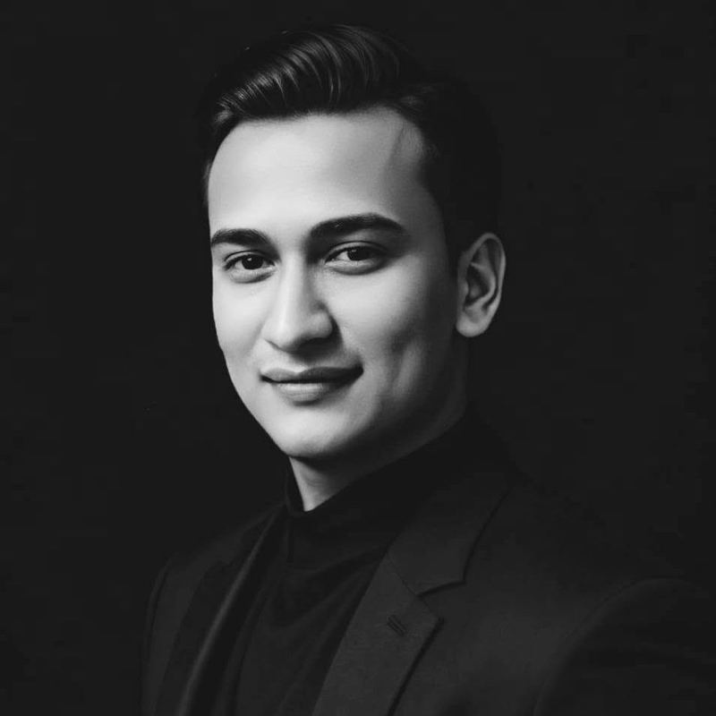 Snehaashish Pathakk, producer, in a black suit and black turtleneck. Black-and-white portrait.